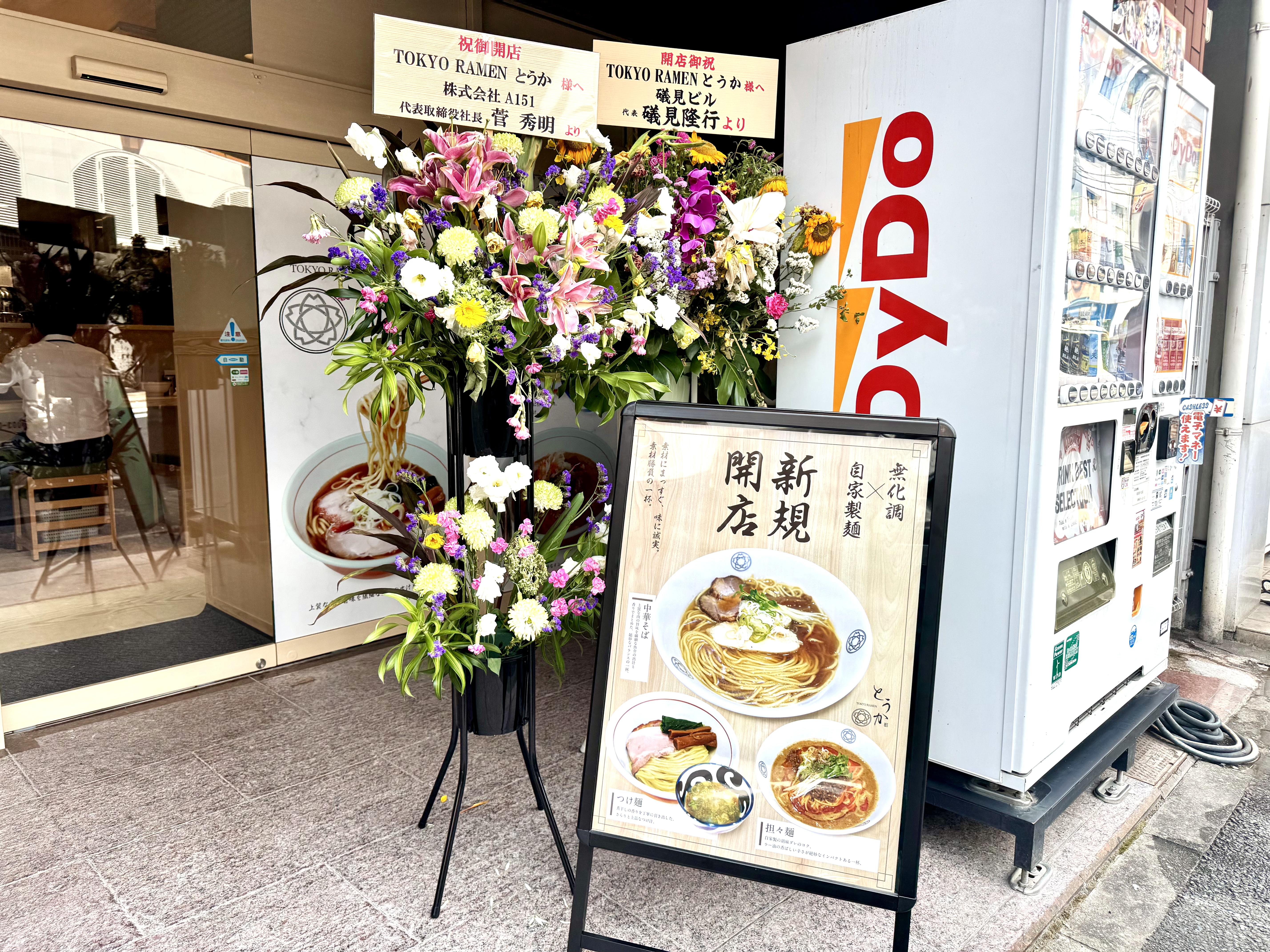 店頭のメニューポスターと祝いの花