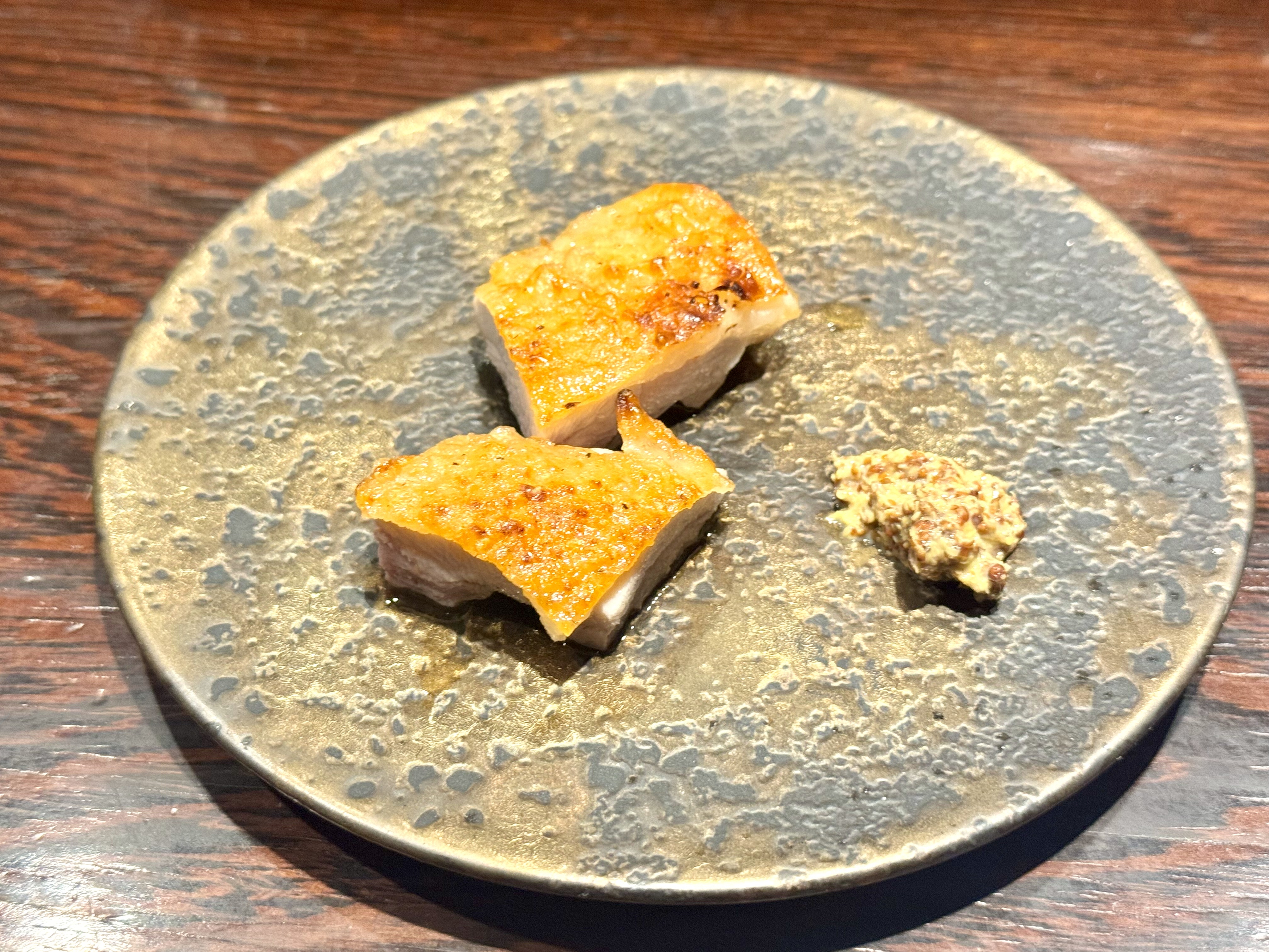 パリパリに焼かれた皮が特徴の鳥をマスタードでいただく