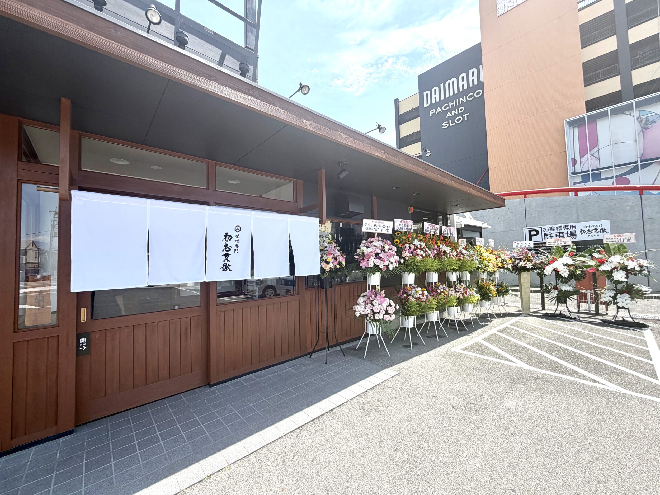 店の暖簾と祝いの花